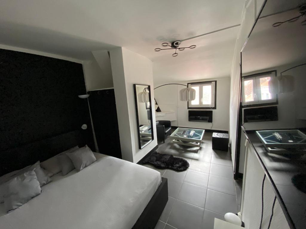 - une chambre avec un lit blanc et un miroir dans l'établissement Suite Apollon - Centre-ville, à Saint-Étienne