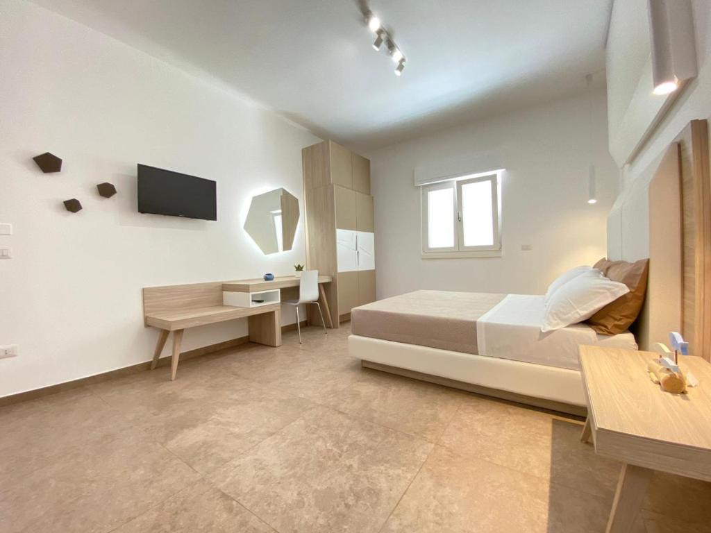 Un dormitorio con una cama, un escritorio y un televisor. en GIARO' APARTMENTS, en Porto Cesareo