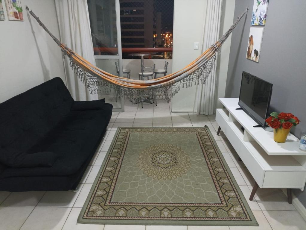 Braga Apartamento Temporada Maceió في ماسيو: غرفة معيشة مع أريكة سوداء وأرجوحة