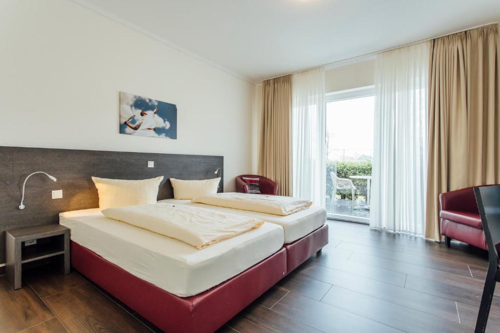 a hotel room with a bed and a chair at Hotel Bloemfontein in Borkum