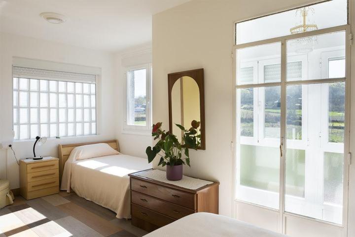 1 dormitorio con cama, espejo y ventana en A Pousa Pensión rural (Camino de Santiago Sanabrés), en Armariz