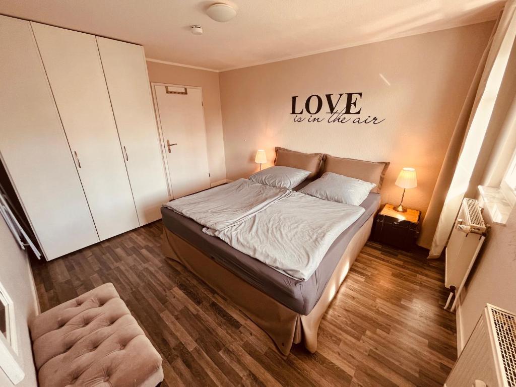 - une chambre avec un lit aux mots « l'amour est sur le mur » dans l'établissement Ferienwohnung Strandeck - Inklusive Strandkorb in den Sommermonaten, à Göhren