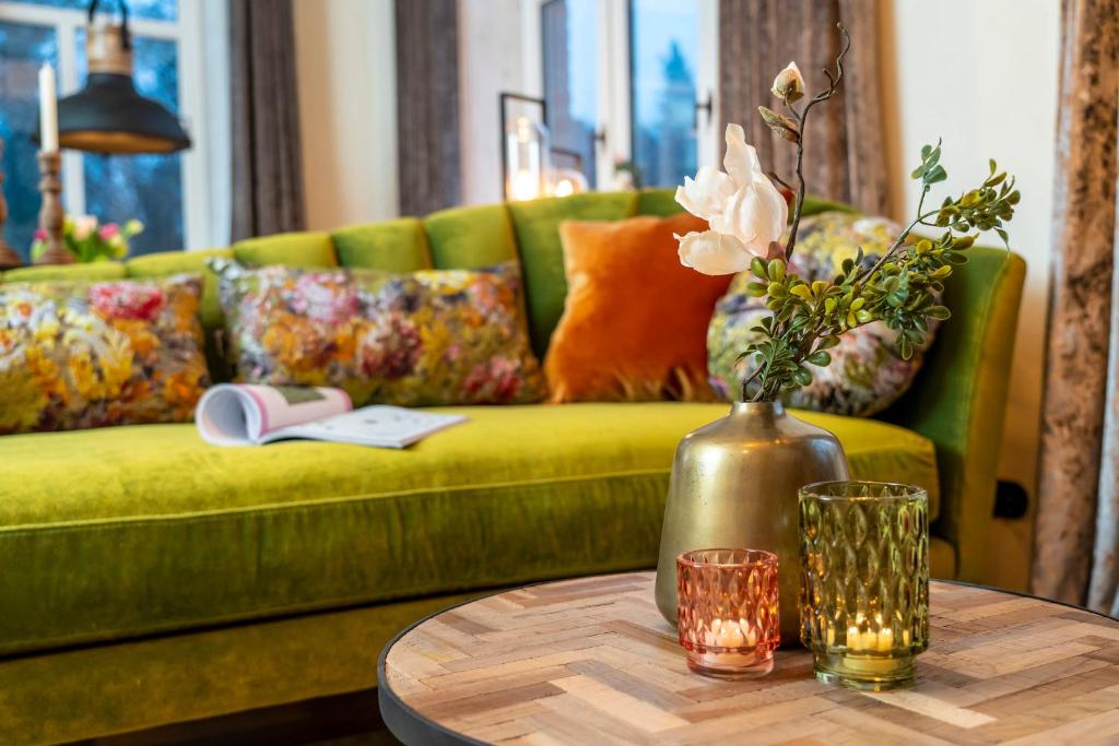 een groene bank met een vaas met bloemen op een tafel bij Apartment Suite in Bad Segeberg