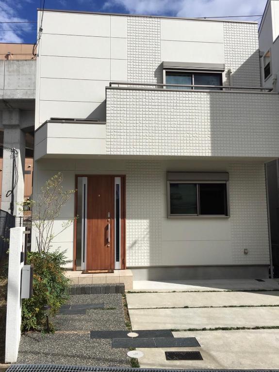 una casa di mattoni bianchi con una porta marrone di Nara Guesthouse Kaede a Nara