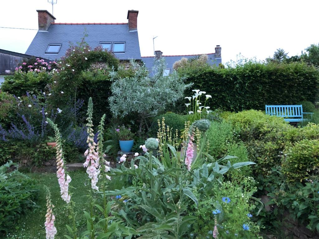 un jardin avec des fleurs et des plantes devant une maison dans l'établissement La chambre du capitaine, à Plérin