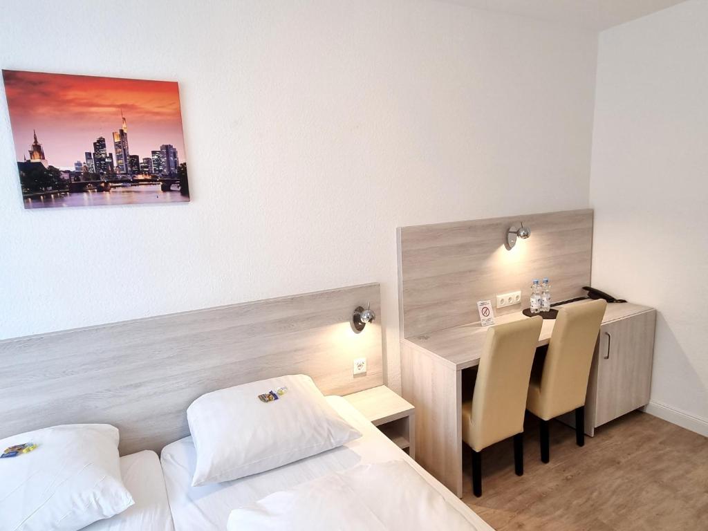 ein Hotelzimmer mit 2 Betten, einem Schreibtisch und einem Tisch in der Unterkunft Adler Hotel Frankfurt in Frankfurt am Main