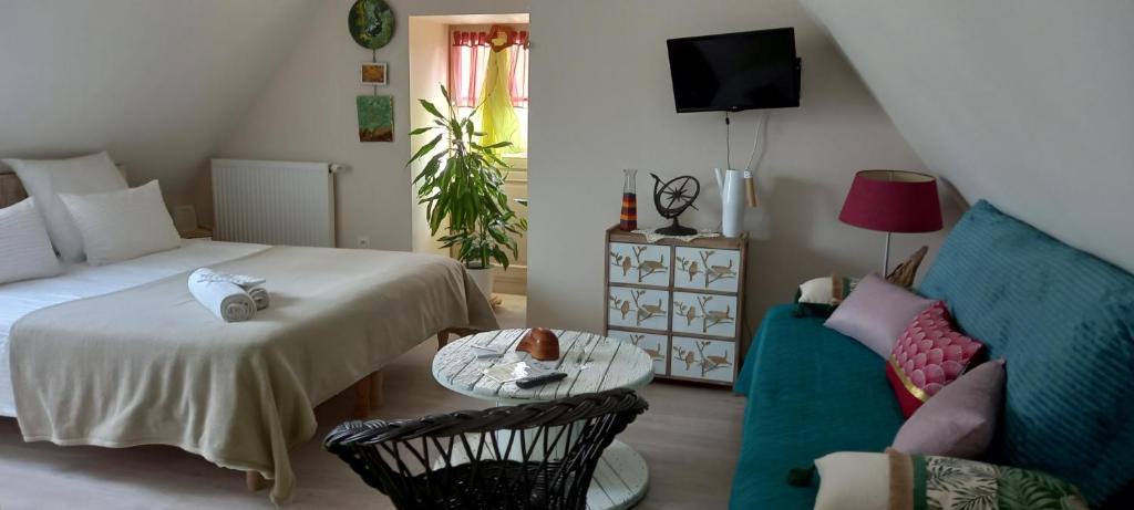 a bedroom with a bed and a couch and a table at Aux penates de Toni Beauval in Céré-la-Ronde