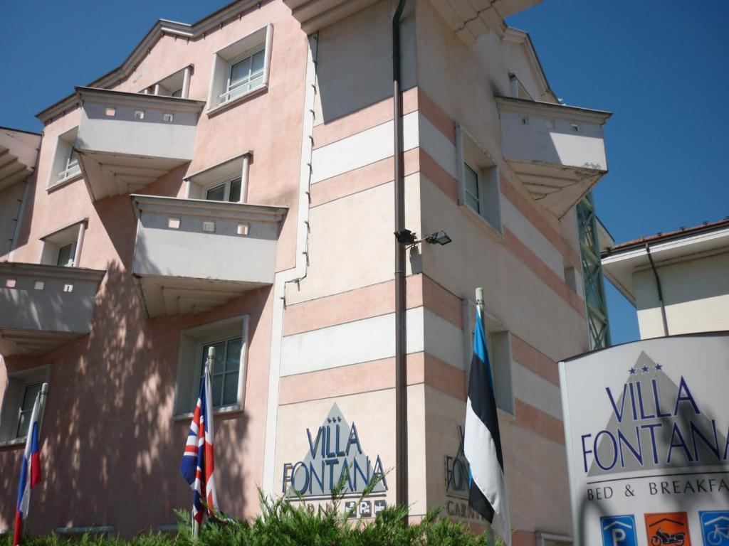 a building with flags in front of it at Hotel Garnì Villa Fontana in Trento