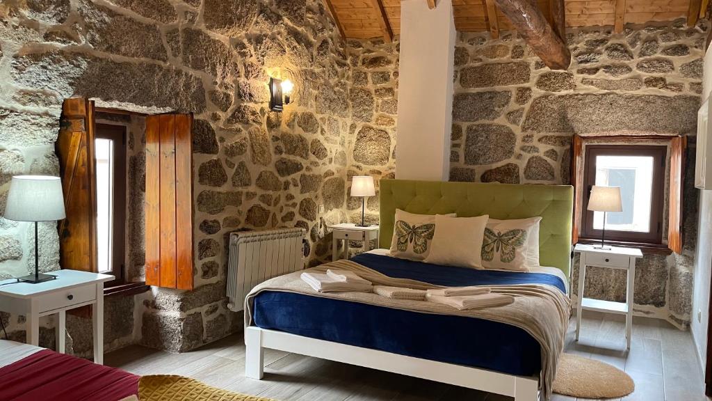 a bedroom with a bed and a stone wall at Aldeia de Pontes - Castro Laboreiro in Castro Laboreiro