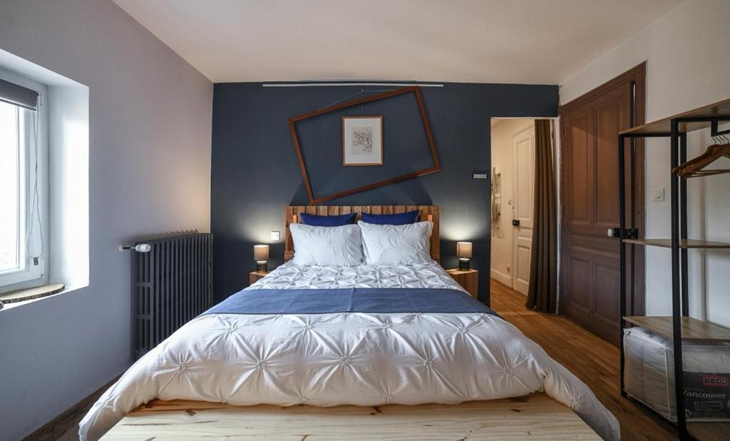 ein Schlafzimmer mit einem großen Bett mit blauer Wand in der Unterkunft La Maison Fleur de Frangipanier in Saint-Genix-sur-Guiers