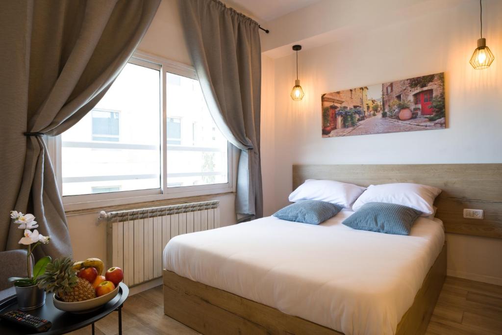 1 dormitorio con 1 cama con ventana y un bol de fruta en Aju Hillel 14 en Jerusalem