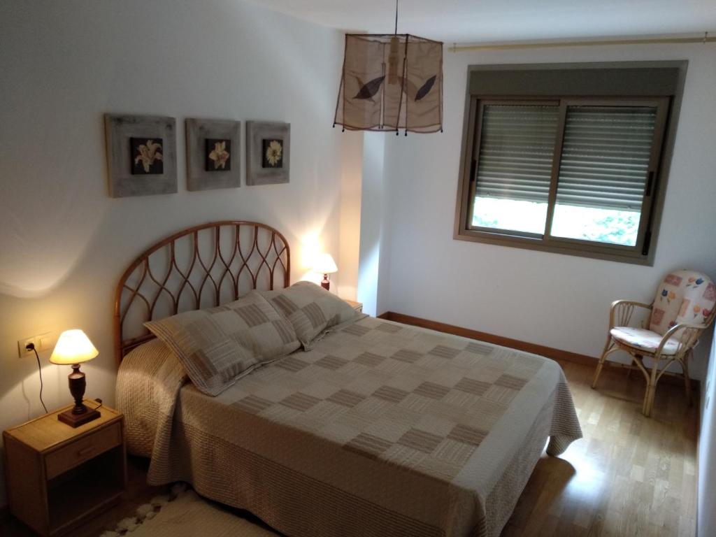 a bedroom with a bed and a window and a chair at Apartamento con encanto in Boiro