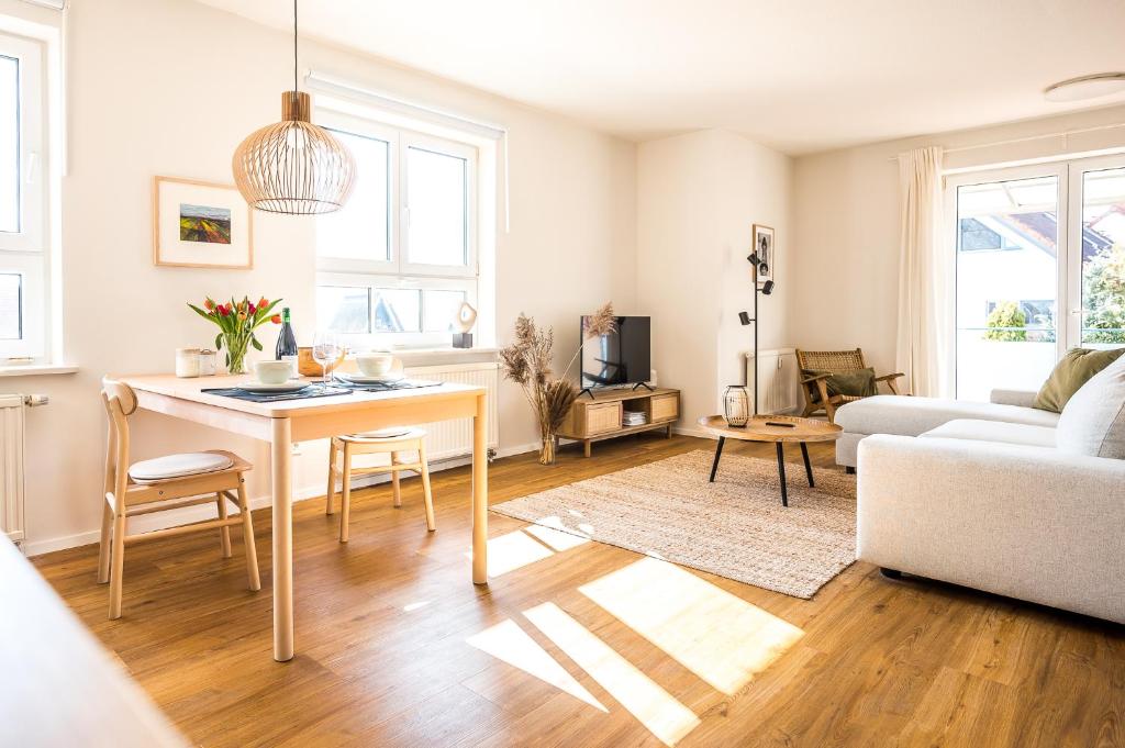 a living room with a table and a couch at Wunderschöne Ferienwohnung mit Feldblick und Balkon (2022 renoviert), mit kostenlosem Wlan und Strandfahrrad, Haustiere erlaubt in Börgerende-Rethwisch