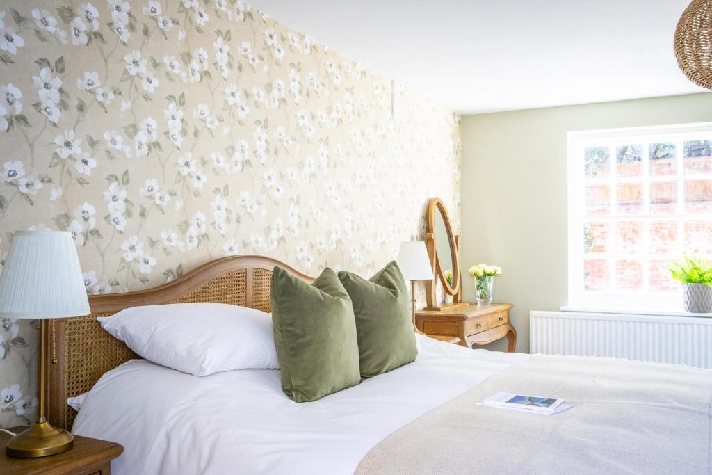 a bedroom with a white bed with green pillows at The White Horse in Faversham