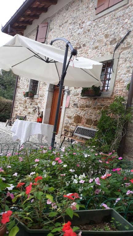 a white umbrella and flowers in front of a building at Alloggio Agrituristico Conte Ottelio in Pradamano