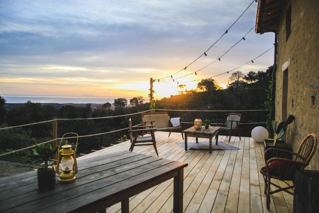 une terrasse en bois avec une table et des chaises et le coucher du soleil dans l'établissement Eco Gîte avec vue sur mer, à Chiatra