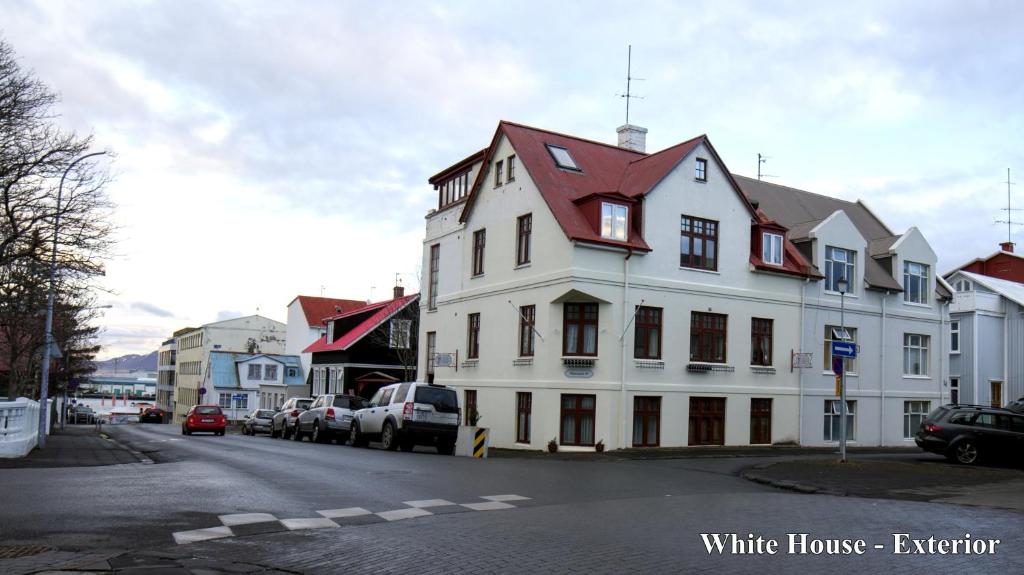 a white house with a red roof on a street at Three Sisters Apartments in Reykjavík