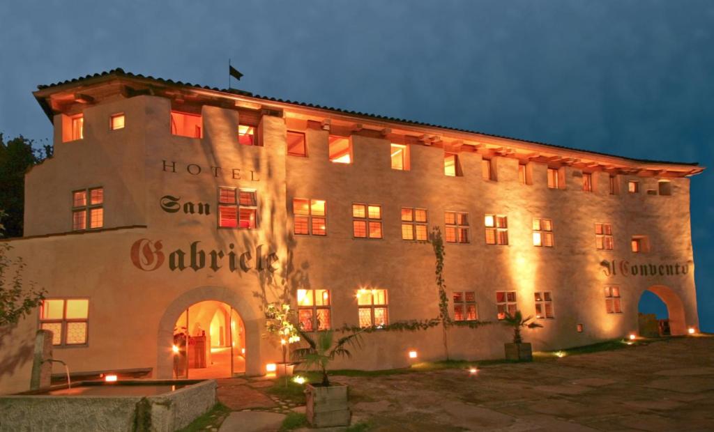 un grand bâtiment avec des lumières allumées la nuit dans l'établissement Hotel San Gabriele, à Rosenheim