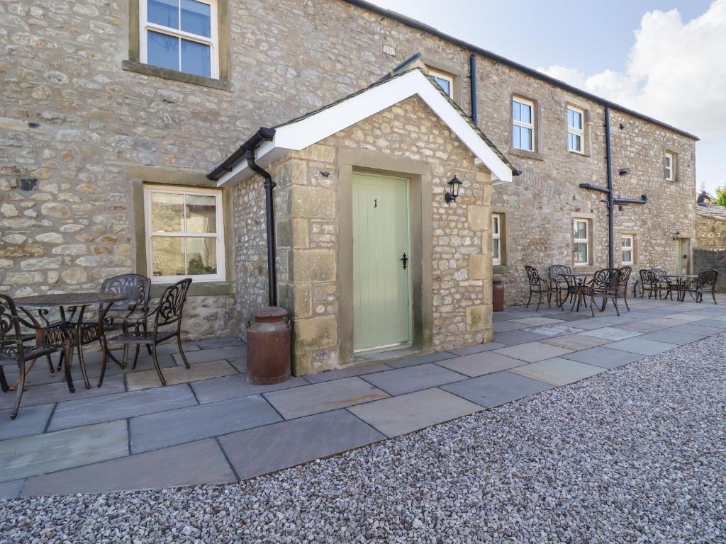 a patio outside of a stone building with a table and chairs at 1 Hull House Cottage in Skipton