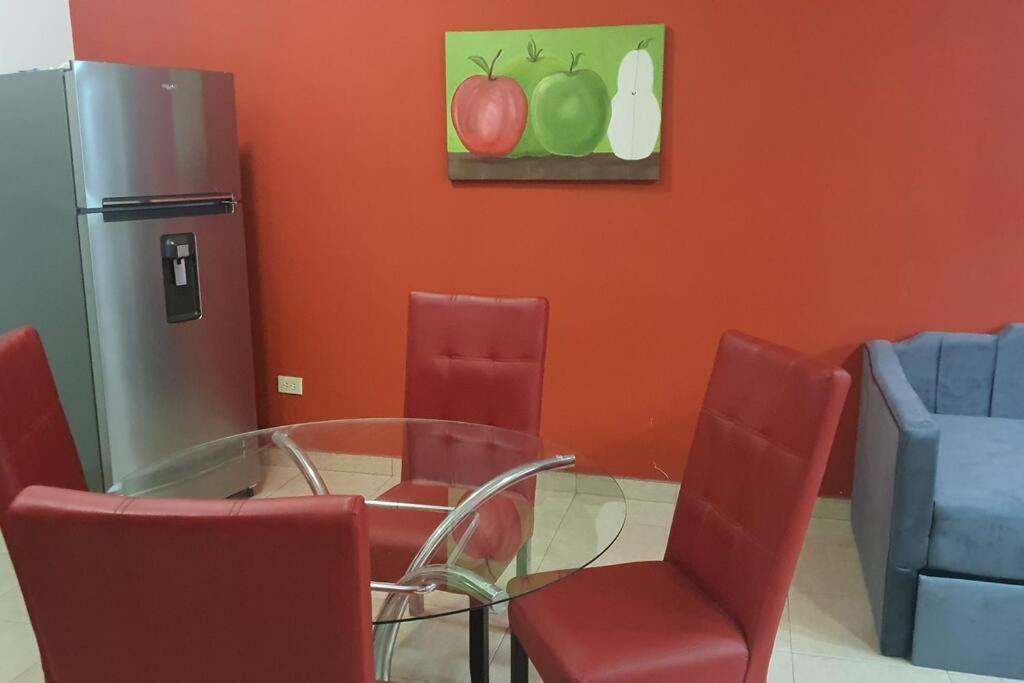 a dining room with a glass table and red chairs at DEPARTAMENTO NUEVO Y CENTRICO EN MITRAS NORTE in Monterrey