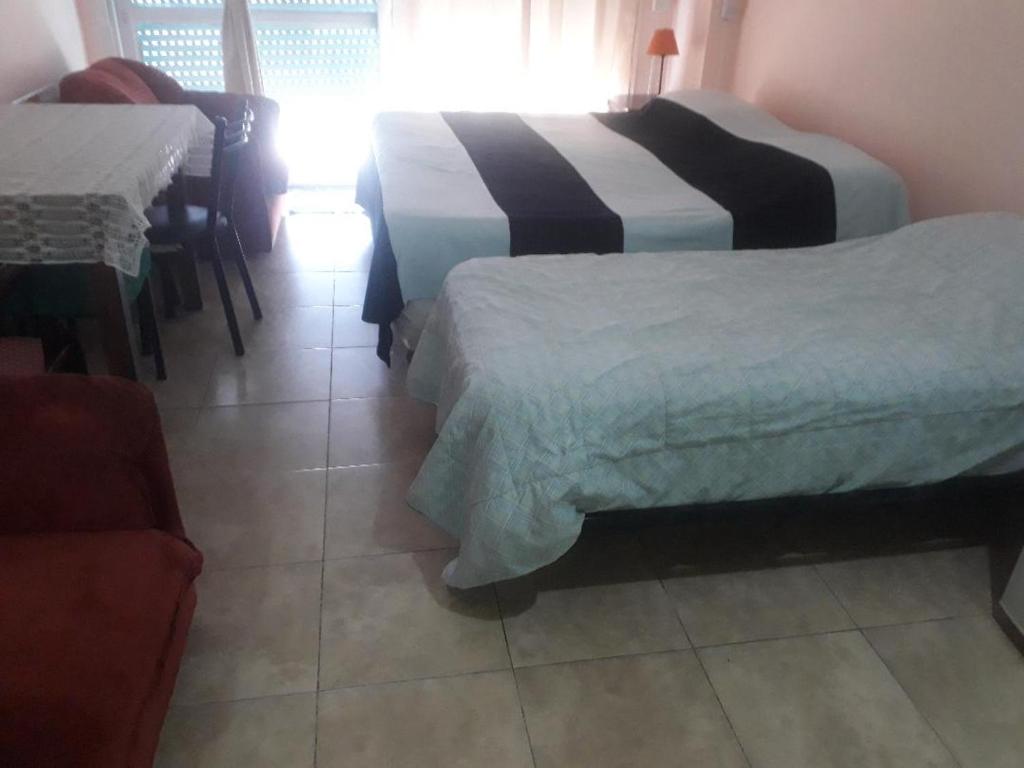 Cette chambre comprend deux lits, une table et une chaise. dans l'établissement CORRIENTES, à Buenos Aires