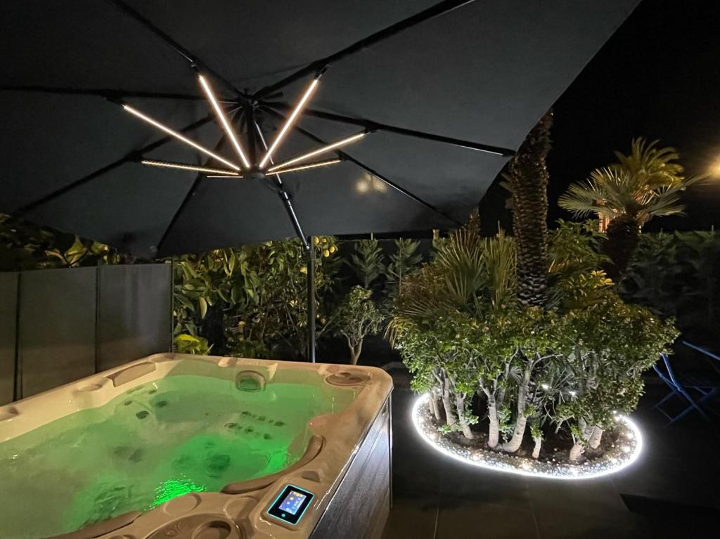 a hot tub with an umbrella in a garden at Luxury Garden Jacuzzi Promenade in Nice