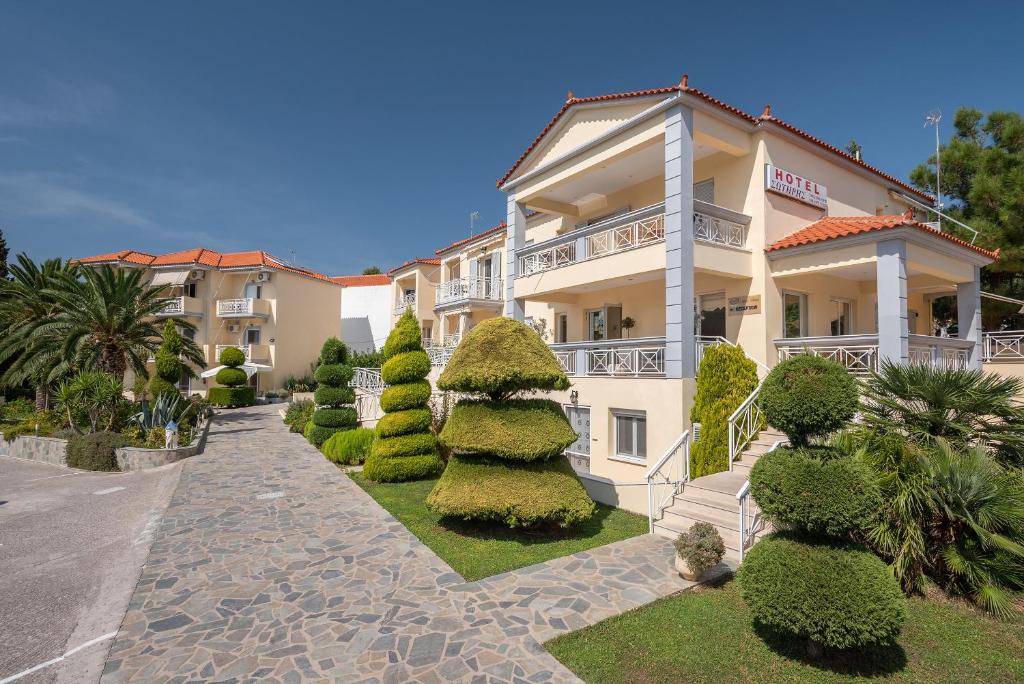 a large building with bushes and trees in front of it at Hotel Sotiris Superior Apartments in Myrina