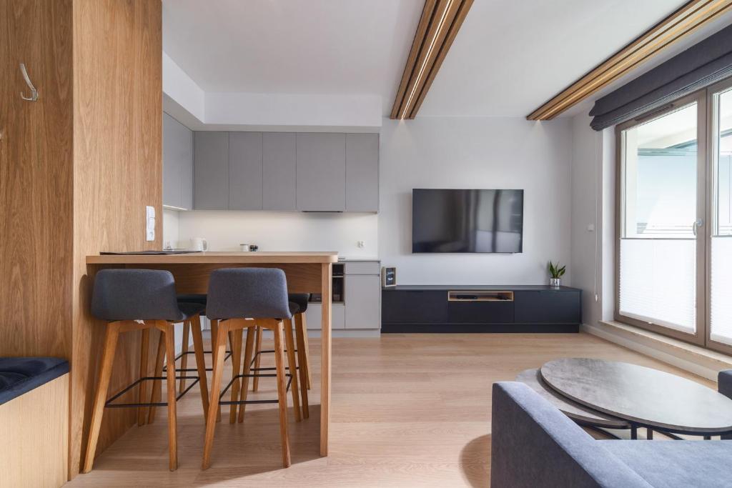 a kitchen and living room with a counter and stools at Apartament GARNIZON in Gdańsk