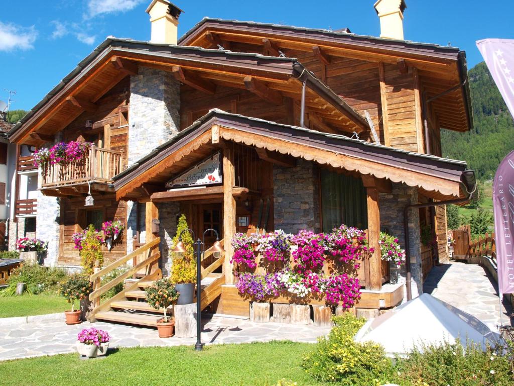 une cabane en rondins avec des fleurs devant elle dans l'établissement Hotel Letterario Locanda Collomb, à La Thuile