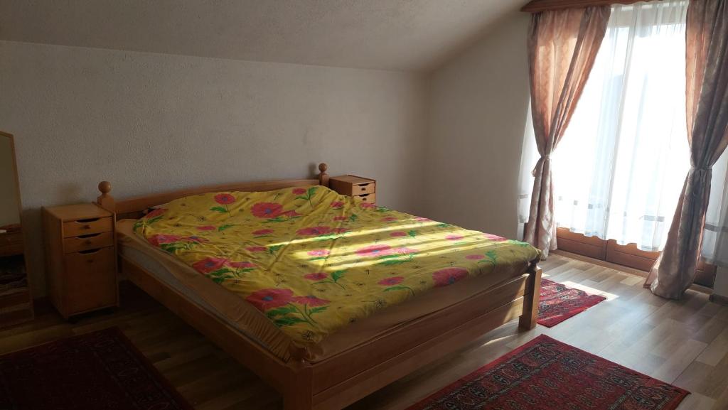 a bedroom with a bed with a floral bedspread and a window at Mini Farm Adi in Cazin
