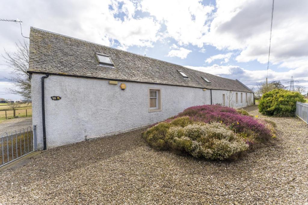 a white building with plants in front of it at East Kelt Farm Cottage in Denny