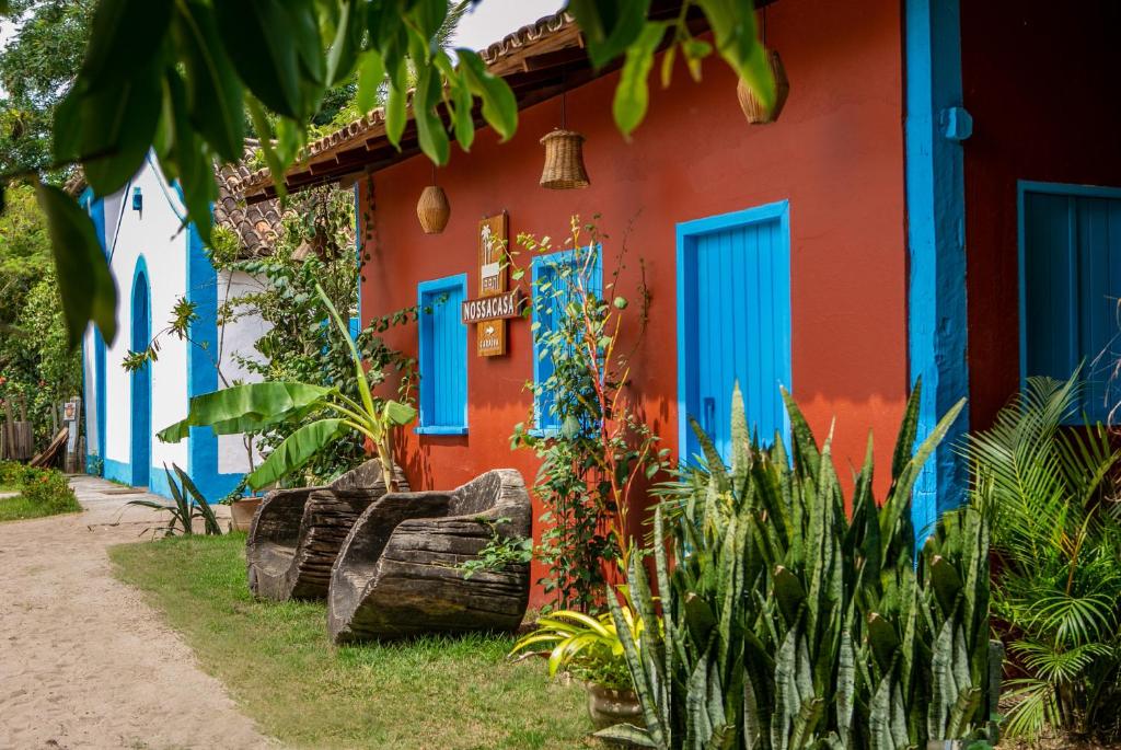 una casa colorida con puertas y plantas azules en Nossa Casa Caraíva - A melhor localização da Vila, en Caraíva