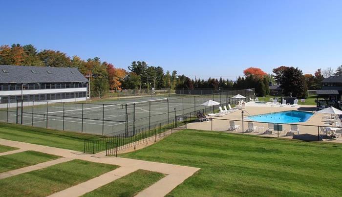 um campo de ténis com piscina em frente a um edifício em Nautical Mile Resort em Wells