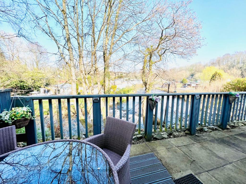 a balcony with two chairs and a fence at Whiskey river chalet-Glan Gwna Holiday Park in Caernarfon