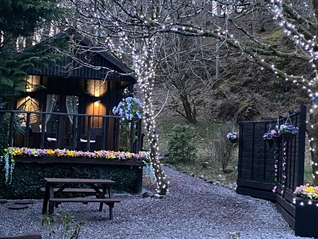 a garden with a bench and a fence with lights at Bluebell lodge in Fort William