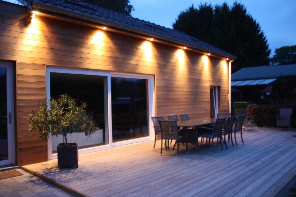 eine Holzterrasse mit einem Tisch, Stühlen und Lampen in der Unterkunft B&B Au coin des sources in Sart-lez-Spa