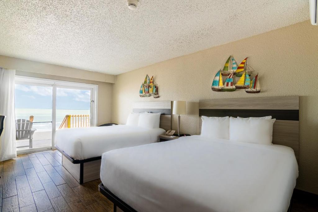 two beds in a hotel room with a view of the ocean at Emerald Beach Hotel Corpus Christi in Corpus Christi