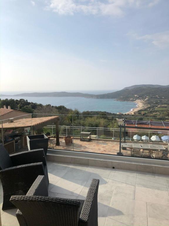 einen Balkon mit Stühlen und Blick auf das Wasser in der Unterkunft Haut de Villa - Vue mer avec Coucher de Soleil in Cargèse