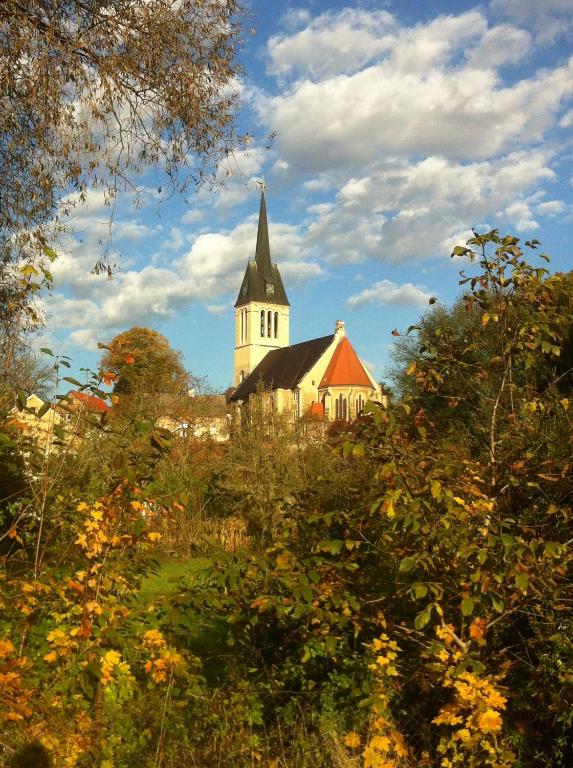 a church with a steeple in the middle of trees at Ferienwohnung Günther am Park in Ditfurt