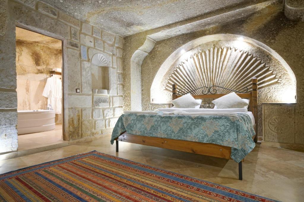 a bedroom with a large bed in a stone wall at Kaya Konak Cave in Nevsehir