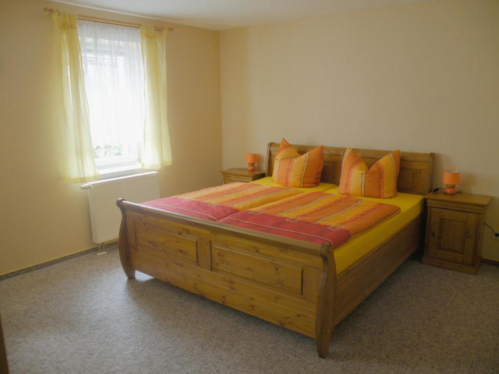 una camera da letto con un grande letto in legno con cuscini arancioni di Am Lindenbaum a Kirnitzschtal