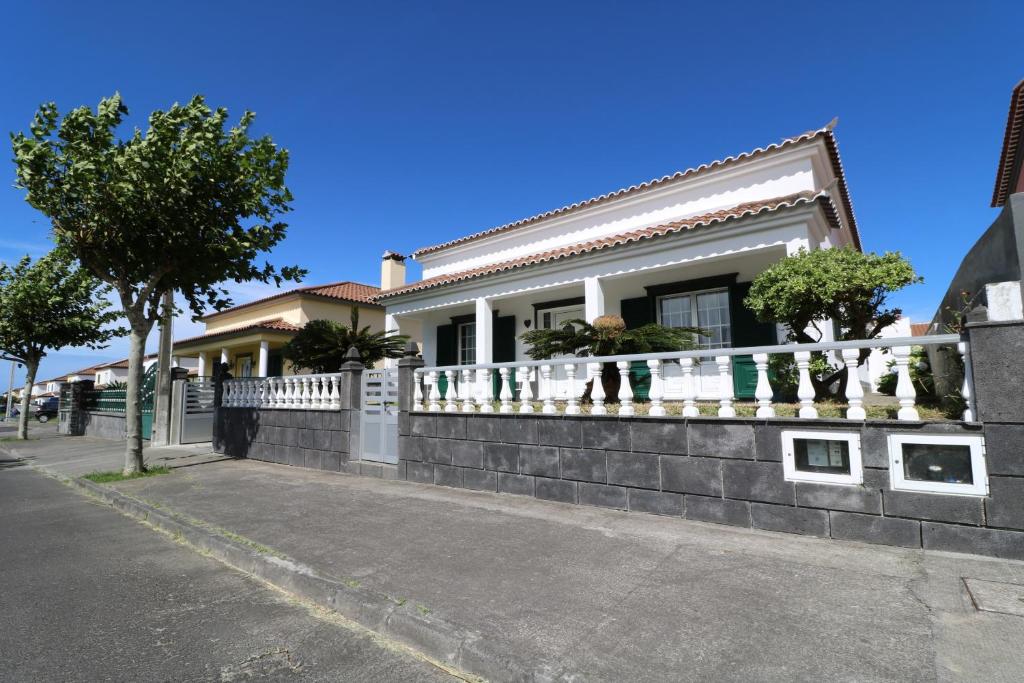 a house with a white fence on a street at Casa das Vinhas in Mosteiros