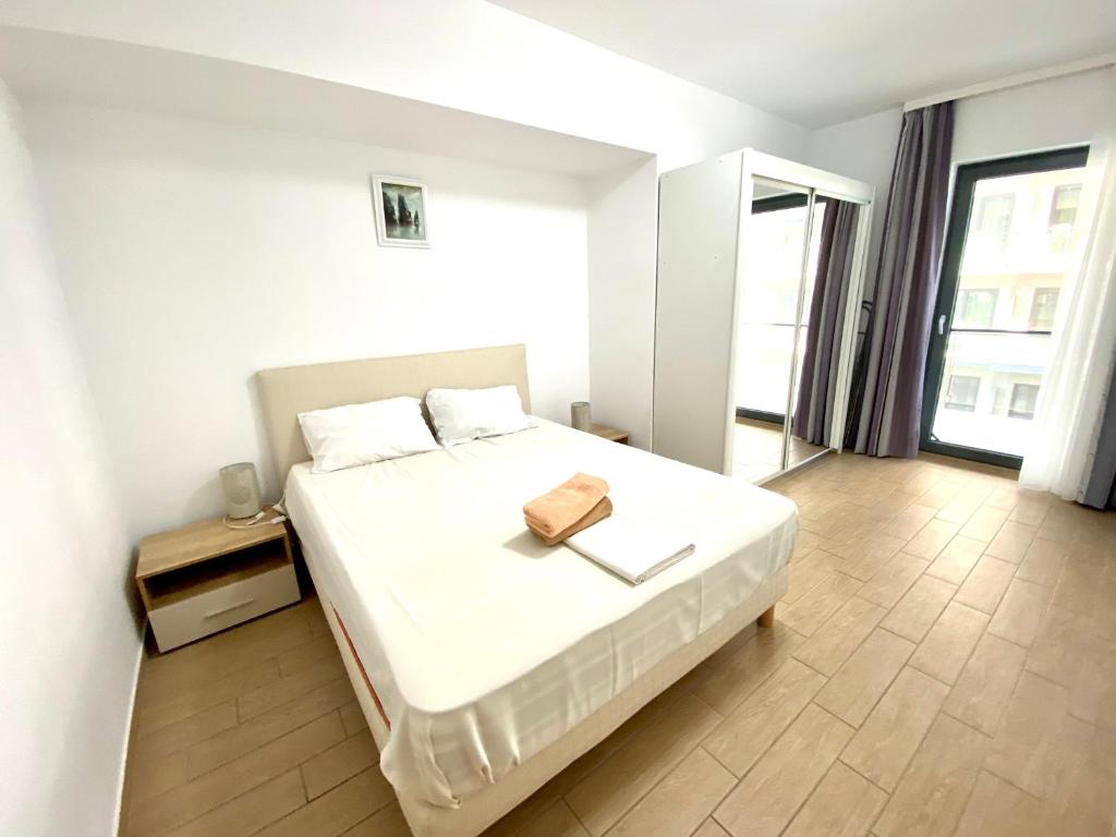 ママイアにあるSunshine Apartament De Silvaのベッドルーム1室(白いベッド1台、茶色の財布付)