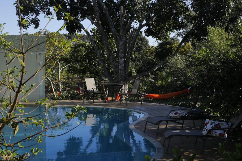 a pool with chairs and a table and a tree at Rancho Litoral Búzios in Búzios