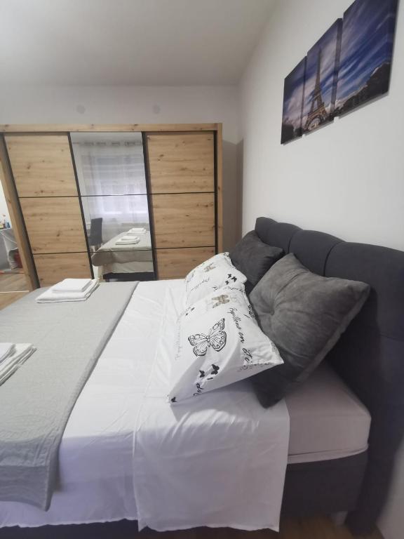a bed with two pillows on top of it at The Location Central Town Apartament in Kragujevac