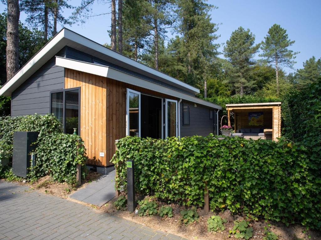 een klein huis met een heg ervoor bij Modern house with roof, located in a holiday park in Rhenen in Rhenen