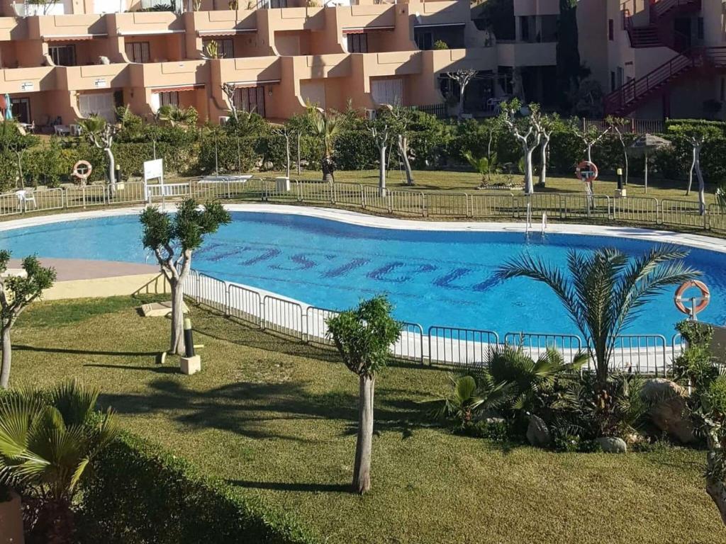 a large swimming pool with palm trees in front of a building at Beautiful Apartment in Almer a with Swimming Pool in Playas de Vera