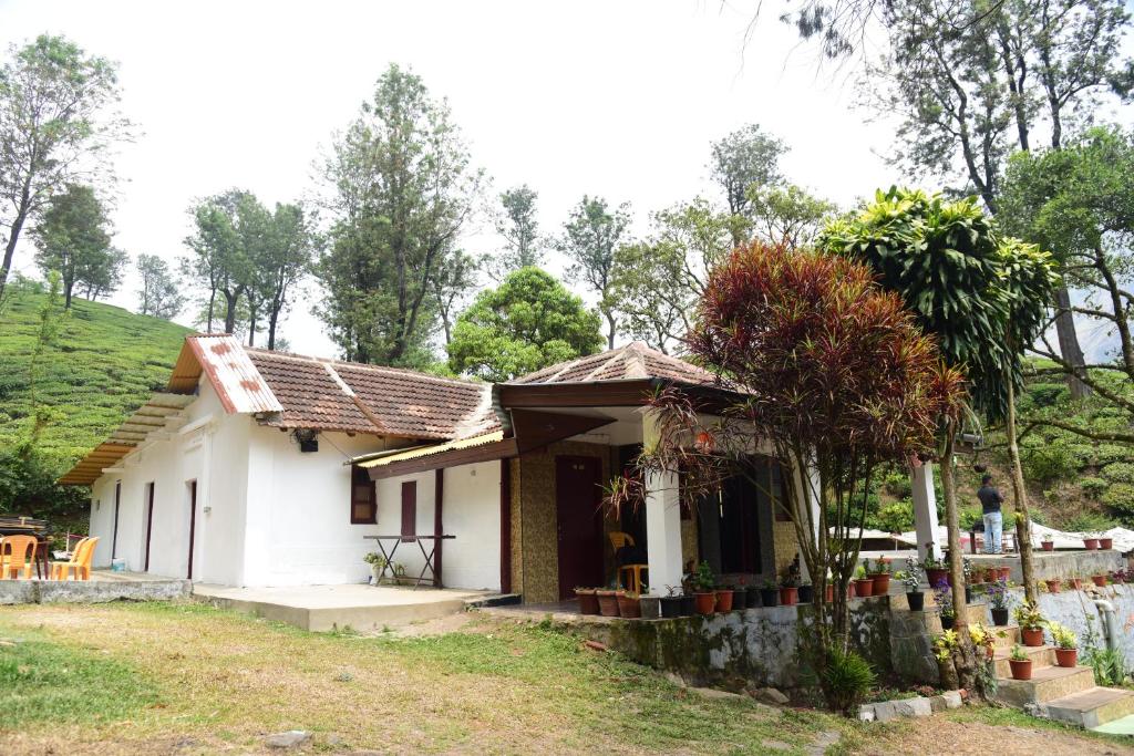 a small white house with a green hill in the background at Munnar Home Stay in Munnar