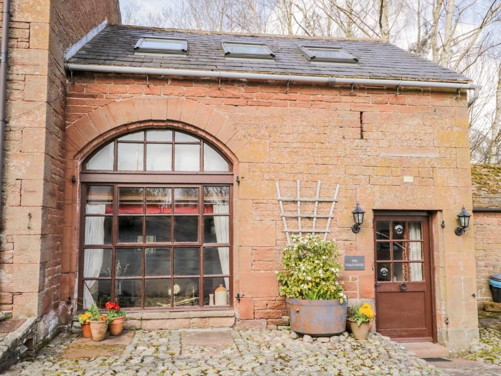 a brick building with a large window and plants at The Coach House in Kirkoswald