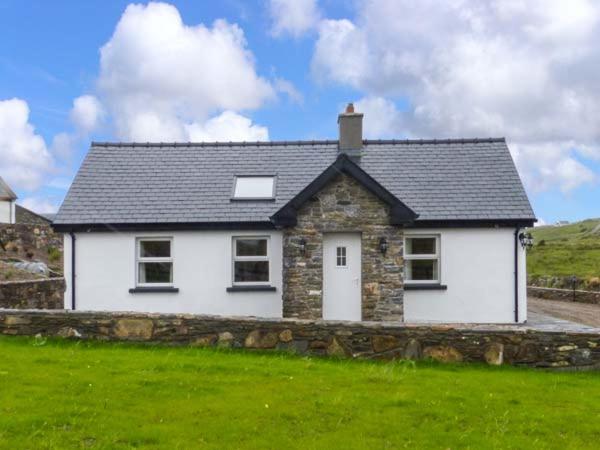 a white house with a stone wall in a field at Farmhouse in Lisdoonvarna